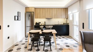 A modern kitchen with wooden cabinets, a stainless steel refrigerator, and a dining area with a hexagonal tile floor. - Modern Minimalist 3BD Apartment in Hilton District (Athens)