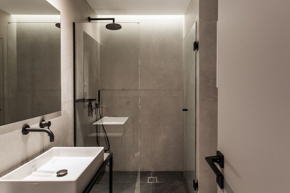 A modern bathroom with a glass-enclosed shower, a white sink, and a mirror.