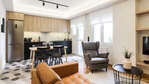 A modern living room with a sofa, a grey armchair, and a small table with a plant. - Modern Minimalist 3BD Apartment in Hilton District (Athens)