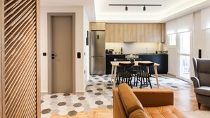A modern kitchen with a central island, wooden cabinets, and a dining area with a table and chairs. - Modern Minimalist 3BD Apartment in Hilton District (Athens)