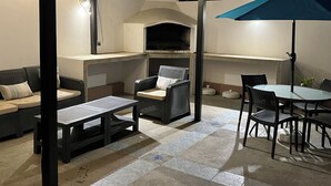An outdoor patio area with a built-in grill, seating, and a table under a blue umbrella. - Large private villa with a pool and jacuzzi, close to the beach (Playas Villamil)