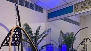 A room with a hanging chair, a sofa, a small table with a decorative item, and a blue-lit column. - Large private villa with a pool and jacuzzi, close to the beach (Playas Villamil)