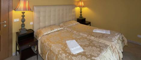 A double bed with a tufted headboard, two bedside tables with lamps, and a wall-mounted light fixture.