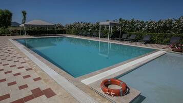 Una piscina rettangolare con bordo piastrellato, lettini e un galleggiante.