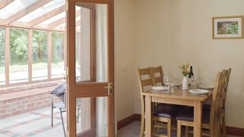 A dining area with a wooden table set for four, a door leading to a patio, and a framed picture on the wall.
