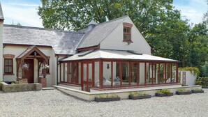 A house with a covered porch, a brick entrance, and a gravel driveway. - 2 bedroom accommodation in Llechryd, near Cardigan (Llechryd, near Cardigan)