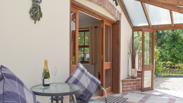 An outdoor patio with a table, chairs, and a bottle of champagne. - 2 bedroom accommodation in Llechryd, near Cardigan (Llechryd, near Cardigan)