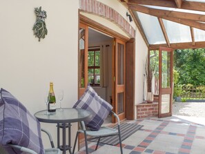Un patio al aire libre con una mesa, sillas y una botella de champán.
