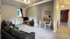 A living room with a black leather sofa, a wooden coffee table, a TV, and a fireplace. - 1 bedroom accommodation in Bowes, near Barnard Castle (Bowes, near Barnard Castle)
