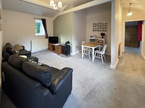 A living room with a black leather sofa, a wooden coffee table, a TV, and a fireplace. - 1 bedroom accommodation in Bowes, near Barnard Castle (Bowes, near Barnard Castle)