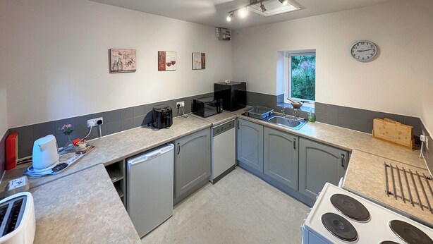 A kitchen with a dishwasher, stove, and a window with a view of greenery. - 1 bedroom accommodation in Bowes, near Barnard Castle (Bowes, near Barnard Castle)