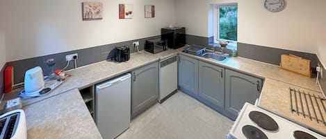 Una cocina con lavavajillas, estufa y ventana con vistas a la vegetación.