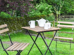 A wooden table with a white teapot, two white cups, and a white jug.