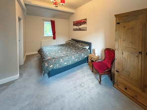 A bedroom with a bed, a chair, a wardrobe, a window, and a radiator.