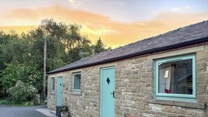 A stone building with multiple windows and doors, a bench outside, and a gravel driveway. - 1 bedroom accommodation in Bowes, near Barnard Castle (Bowes, near Barnard Castle)