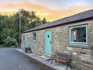 A stone building with multiple windows and doors, a bench outside, and a gravel driveway. - 1 bedroom accommodation in Bowes, near Barnard Castle (Bowes, near Barnard Castle)