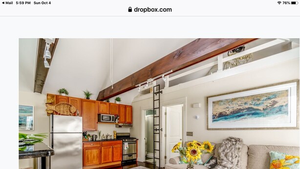 Un vaste espace de vie comprenant une cuisine, une chambre en mezzanine et une grande fenêtre.