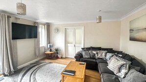 Una sala de estar con un sofá, una mesa de centro, un televisor y una puerta.