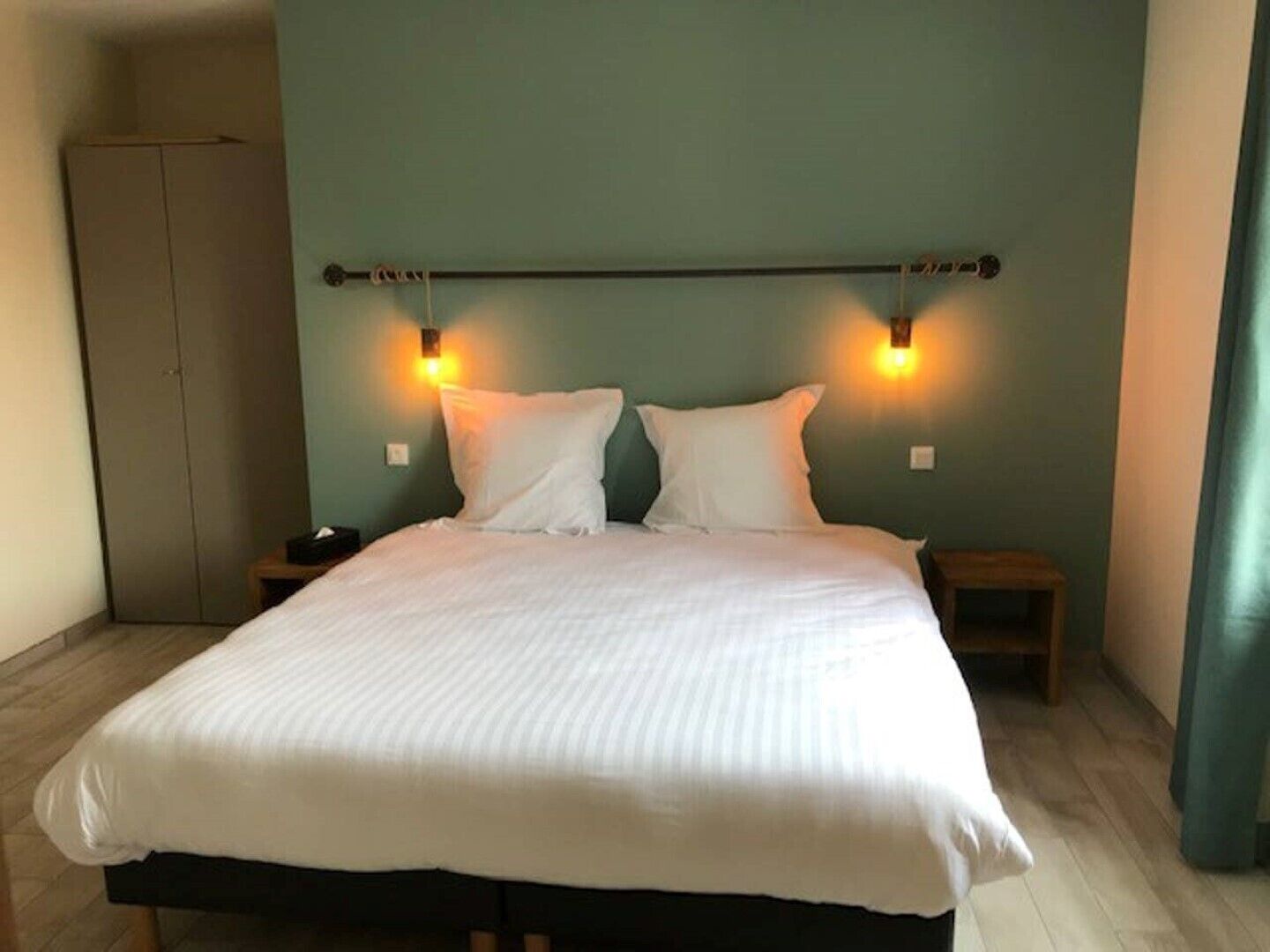 A bedroom with a bed, two bedside tables, and a wardrobe.