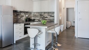 Una cocina moderna con armarios blancos, un salpicadero gris y una isla central con taburetes de bar.