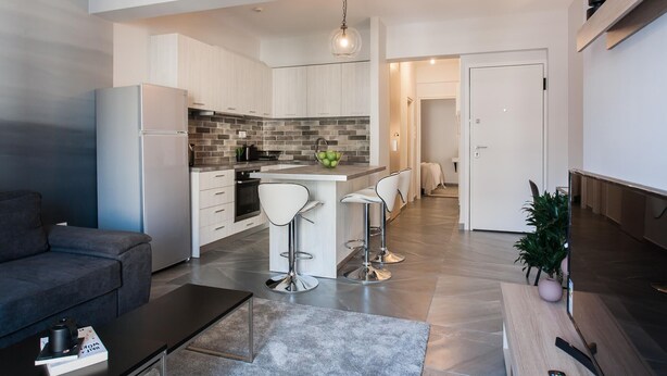 Una cocina moderna con armarios blancos, salpicadero gris y una isla central con taburetes.