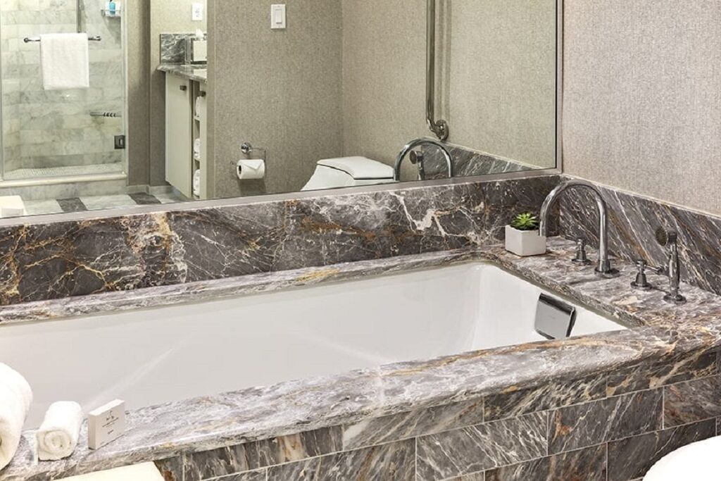 A modern bathroom with a marble sink, a large mirror, and a glass shower enclosure.