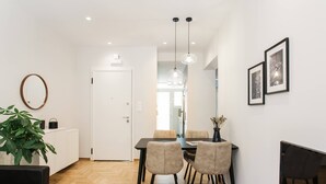 A modern dining area with a wooden herringbone floor, a central table with four chairs, pendant lighting, and framed artwork on the wall. - Peaceful 2BD Apartment in Kolonaki (Athens)