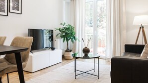 A modern living room with a flat-screen TV, a sofa, a dining table, and a potted plant. - Peaceful 2BD Apartment in Kolonaki (Athens)