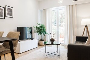 Una sala de estar moderna con una televisión de pantalla plana, un sofá, una mesa de comedor y una planta en maceta.