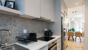 A modern kitchen with a stainless steel sink, a black coffee maker, and a built-in oven. - Peaceful 2BD Apartment in Kolonaki (Athens)