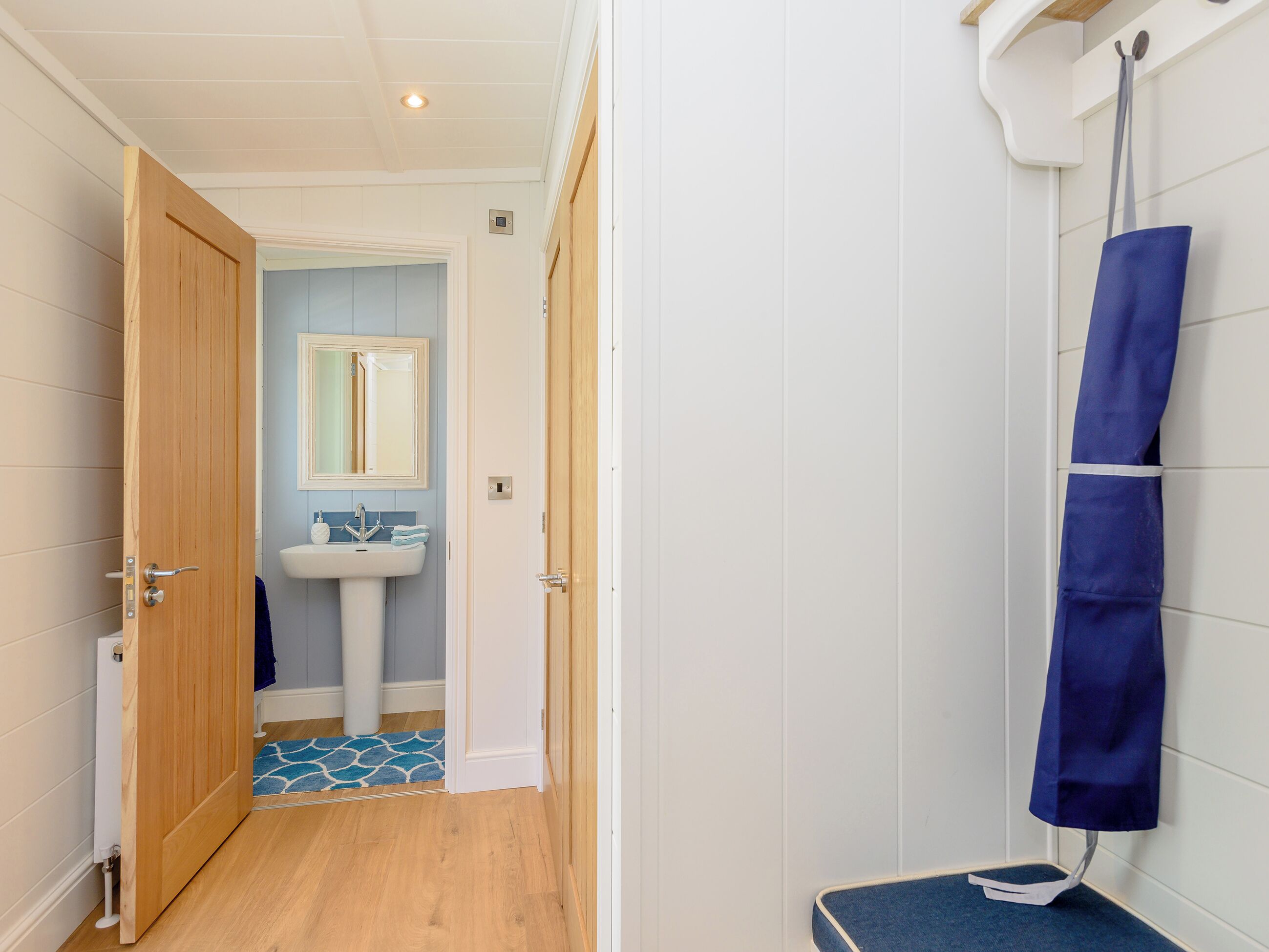 A bathroom with a wooden door, a sink, a mirror, and a shower area.