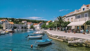 Un pueblo costero con aguas cristalinas, barcos amarrados a la orilla y edificios de arquitectura tradicional.