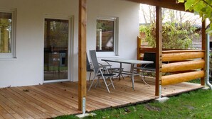 A covered patio with a table and chairs, wooden deck, and a view of the surrounding garden. - Bungalow in Boergerende-rethwisch mit Sauna (Boergerende-Rethwisch)