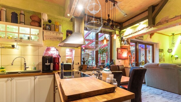 Una cocina acogedora con encimeras de madera, una cafetera y una lámpara colgante.