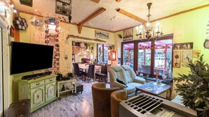 Una sala de estar acogedora y rústica con televisor, un mueble verde y asientos cómodos.