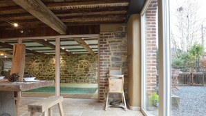 A rustic interior with stone walls, a wooden bench, and a view of the outdoors. - Country Home in Theux With Pool & Sauna (Theux)