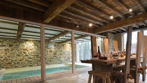A spa area with a stone wall, a wooden ceiling, and a wooden bar with glasses and pine cones. - Country Home in Theux With Pool & Sauna (Theux)