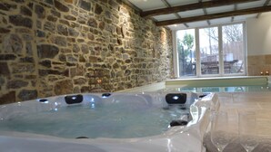 A stone-walled room with a hot tub, a glass-enclosed pool, and a view of the outdoors. - Country Home in Theux With Pool & Sauna (Theux)