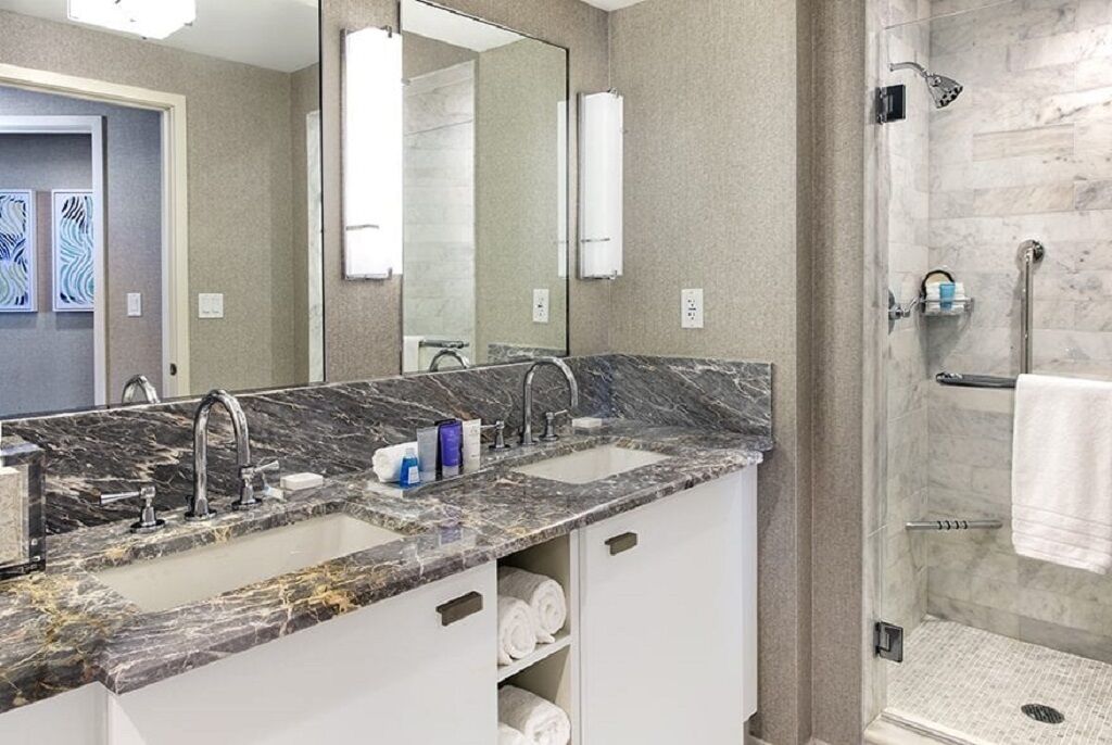A bathroom with two sinks, a large mirror, and a walk-in shower.