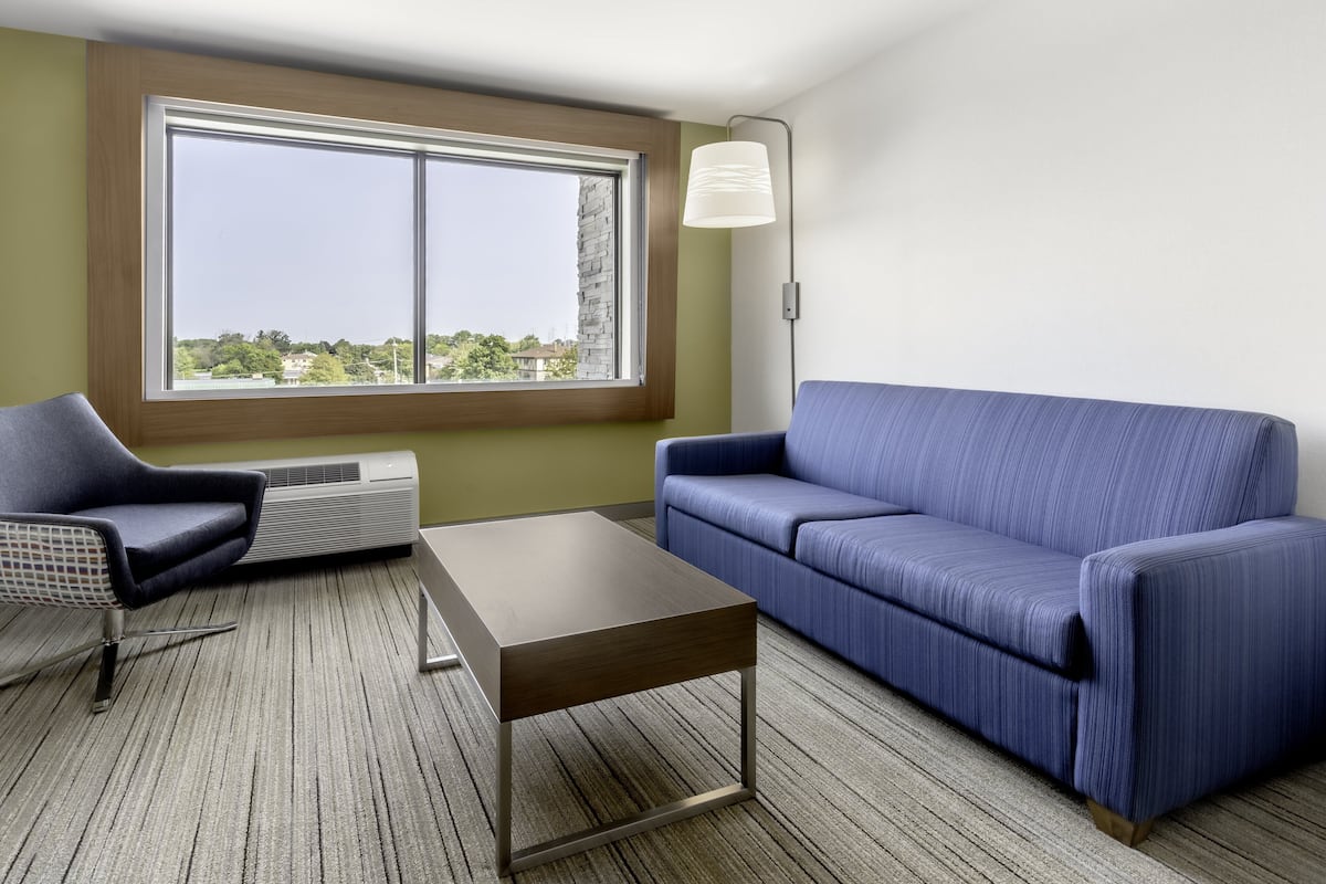 A modern living room with a large window, a blue sofa, a dark wooden coffee table, and a modern chair.