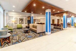 A hotel lobby with a patterned carpet, seating areas, and a reception desk. - Holiday Inn Express Milwaukee West Allis by IHG (Milwaukee)