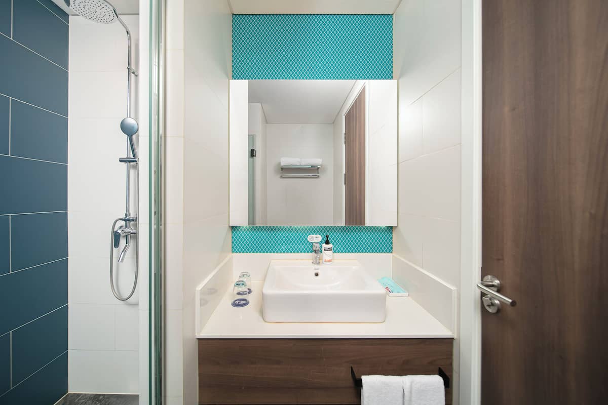 A bathroom with a shower, a sink, and a mirror.