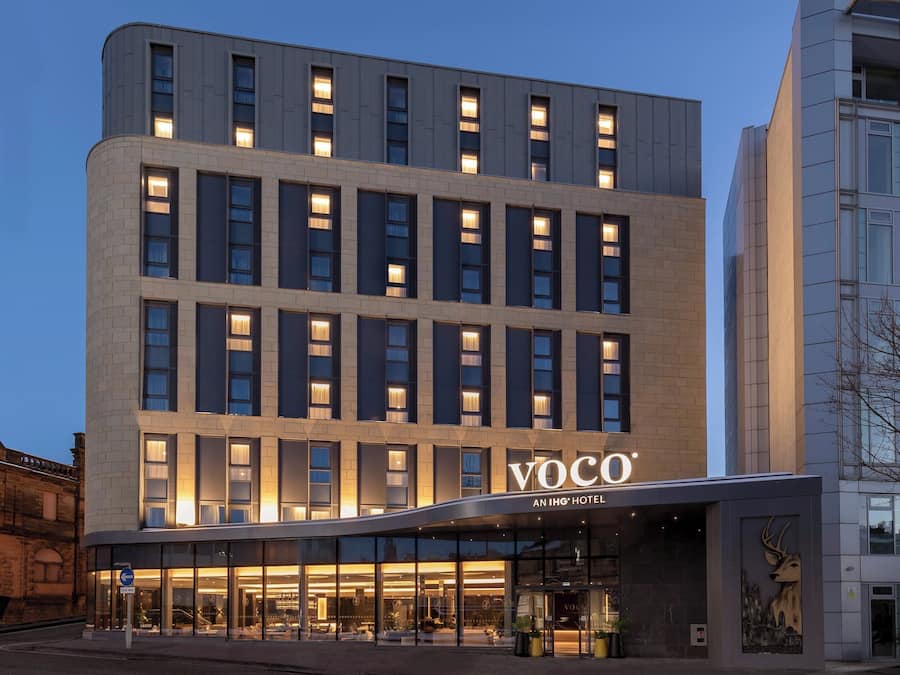 Un moderno edificio de hotel con fachada plana, amplias ventanas y un llamativo letrero 'Voco'.