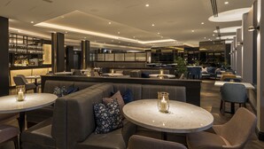 A modern restaurant with round tables, cushioned seating, and ambient lighting. - voco Edinburgh-Haymarket by IHG (Edinburgh)