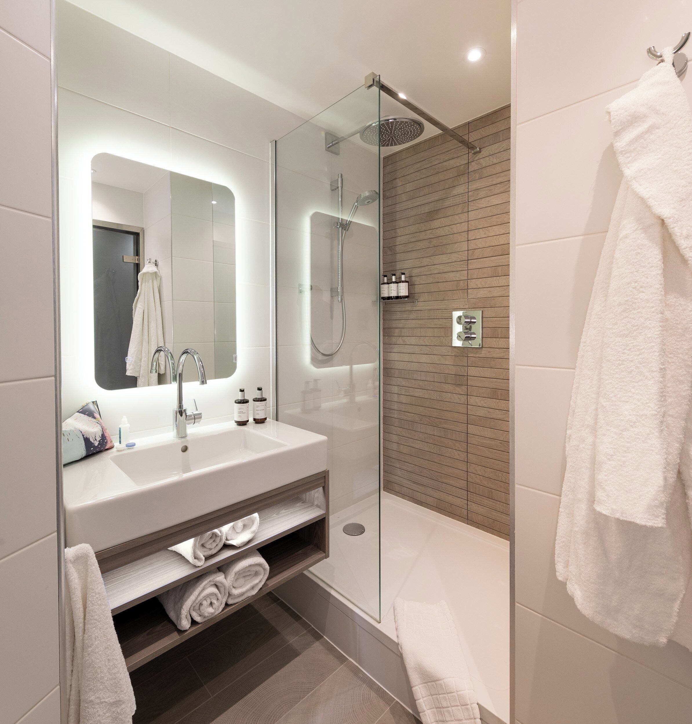 Une salle de bain moderne avec une douche à parois de verre, un meuble-lavabo avec miroir et un porte-serviettes.
