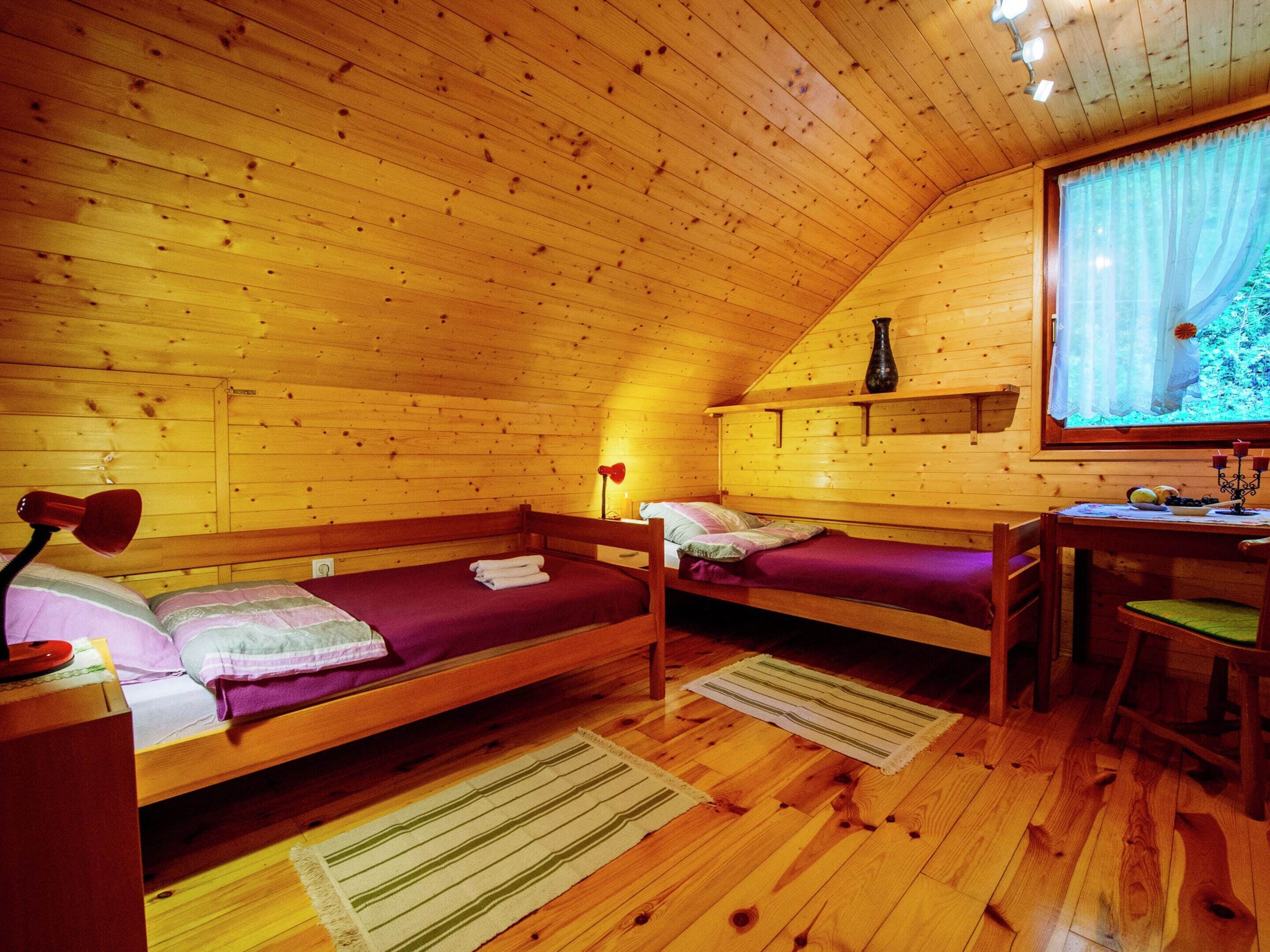 Una cabaña acogedora con dos literas de madera, un escritorio con silla y un ventanal con vistas a la vegetación.