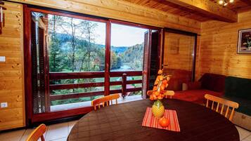 Una cabaña de madera con una amplia mesa de comedor, sillas y vistas a un área boscosa a través de grandes ventanales.