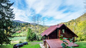 A wooden cabin with a red roof, surrounded by lush greenery and a lake. - Serene Holiday Home in Dolus With Private Garden (Brod Moravice)