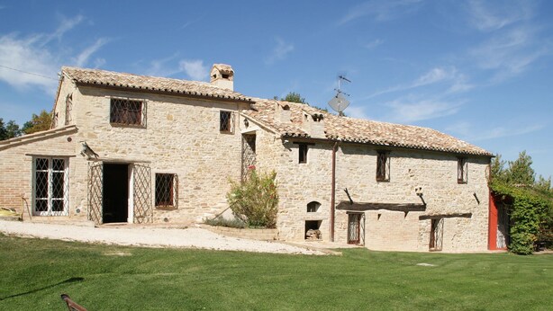 A stone building with a tiled roof, a small garden, and a bench. - Belvilla by OYO Appartamento del Caminetto (Treia)