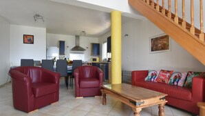 A living room with a wooden coffee table, two red sofas, and a staircase. - Courry Views: Pool & Nature (Courry)